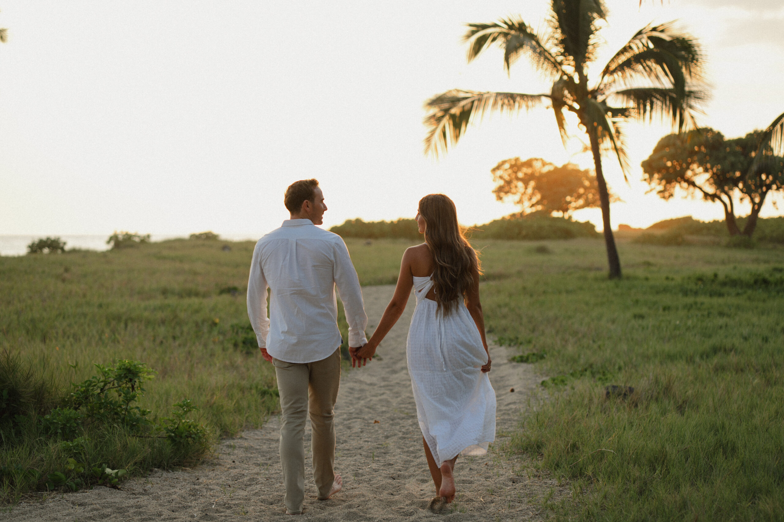 engaged-couple-walking-holding-hands-on-a-sandy-path-on-a-florida-beach-at-sunset